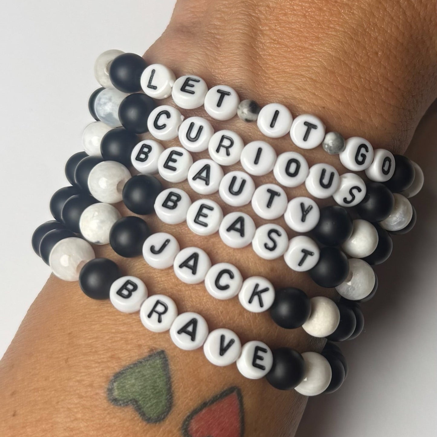 Bracelets with motivational phrases on a wrist against a white background